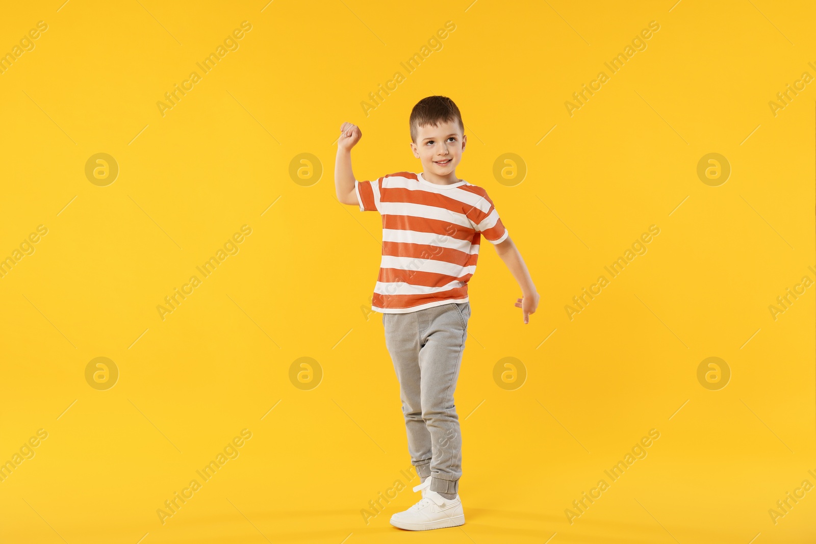 Happy little boy dancing on orange background Photo of Happy little boy dancing on orange background
