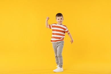 Photo of Happy little boy dancing on orange background