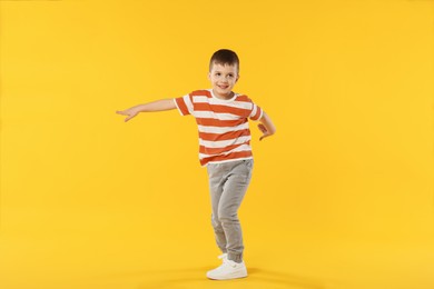 Photo of Happy little boy dancing on orange background