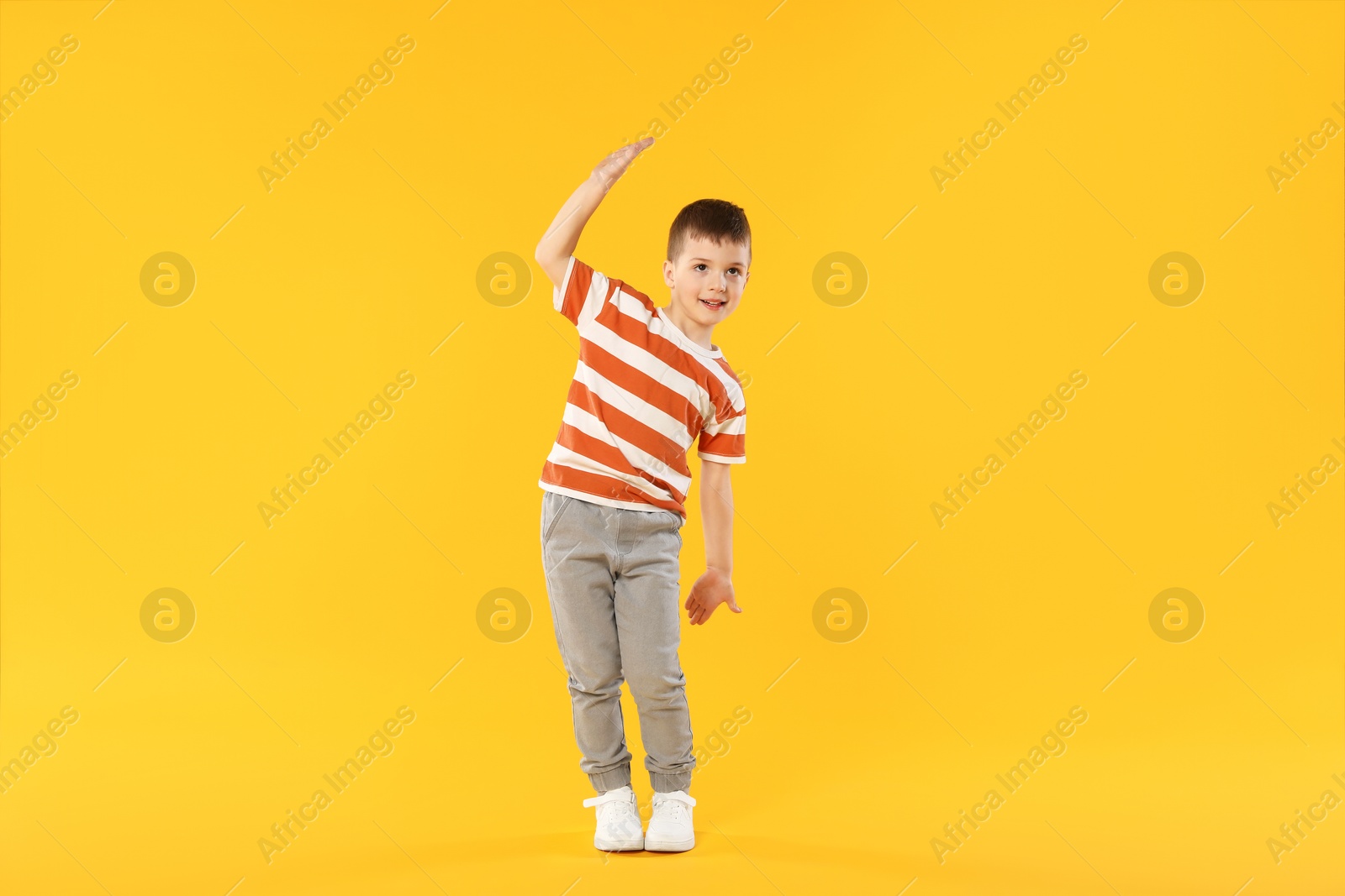 Happy little boy dancing on orange background Photo of Happy little boy dancing on orange background