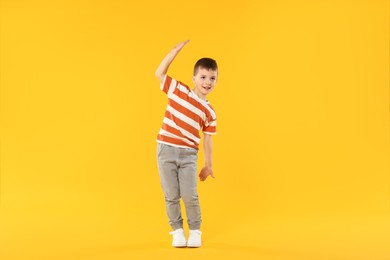 Photo of Happy little boy dancing on orange background