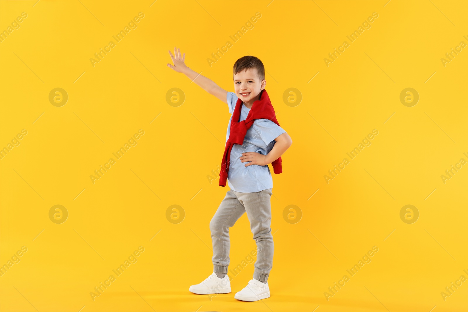 Happy little boy dancing on orange background Photo of Happy little boy dancing on orange background