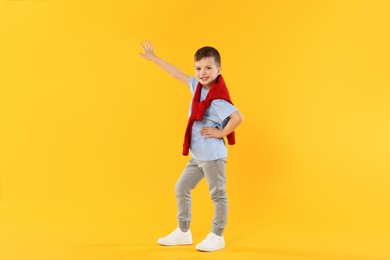 Photo of Happy little boy dancing on orange background