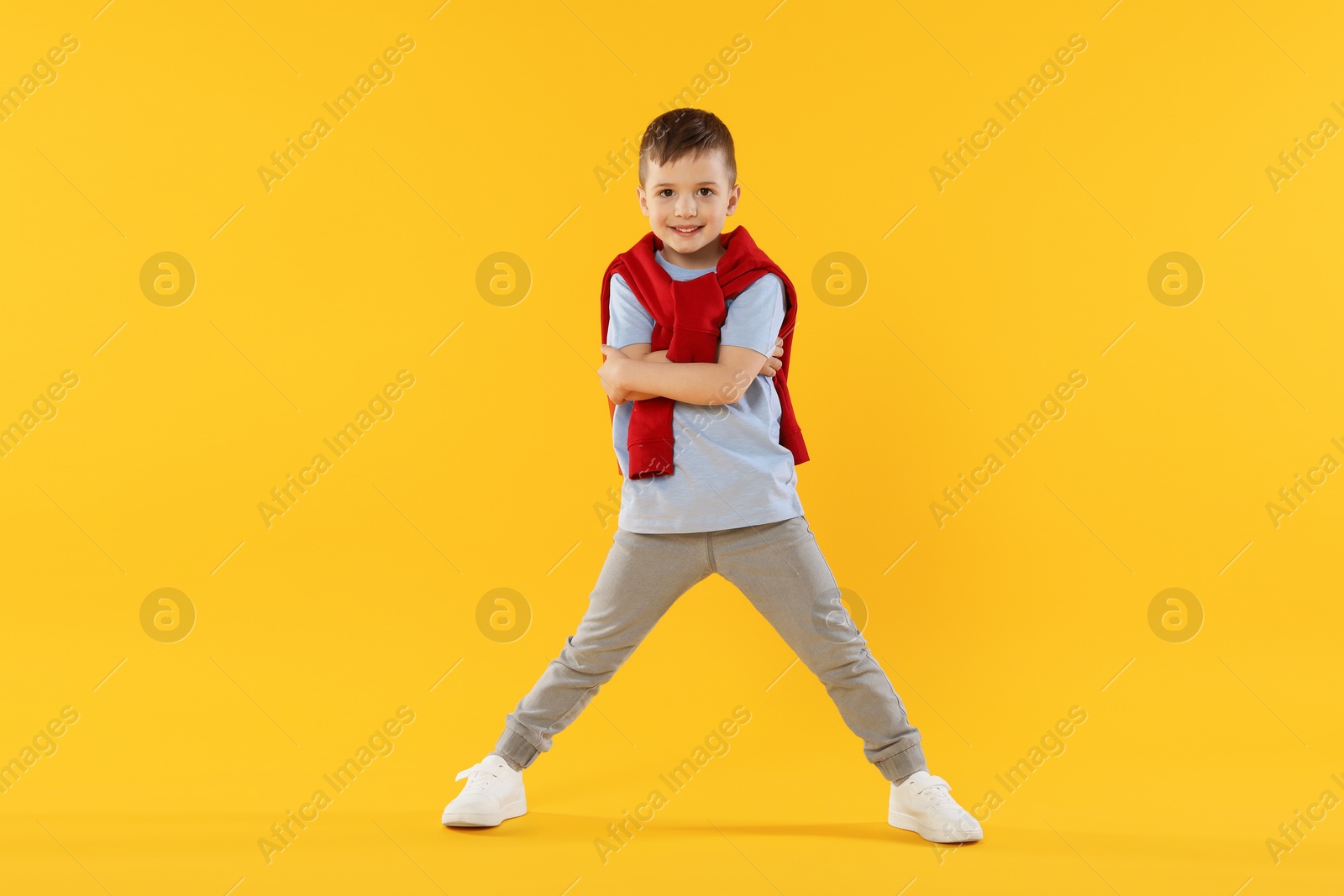 Happy little boy dancing on orange background Photo of Happy little boy dancing on orange background