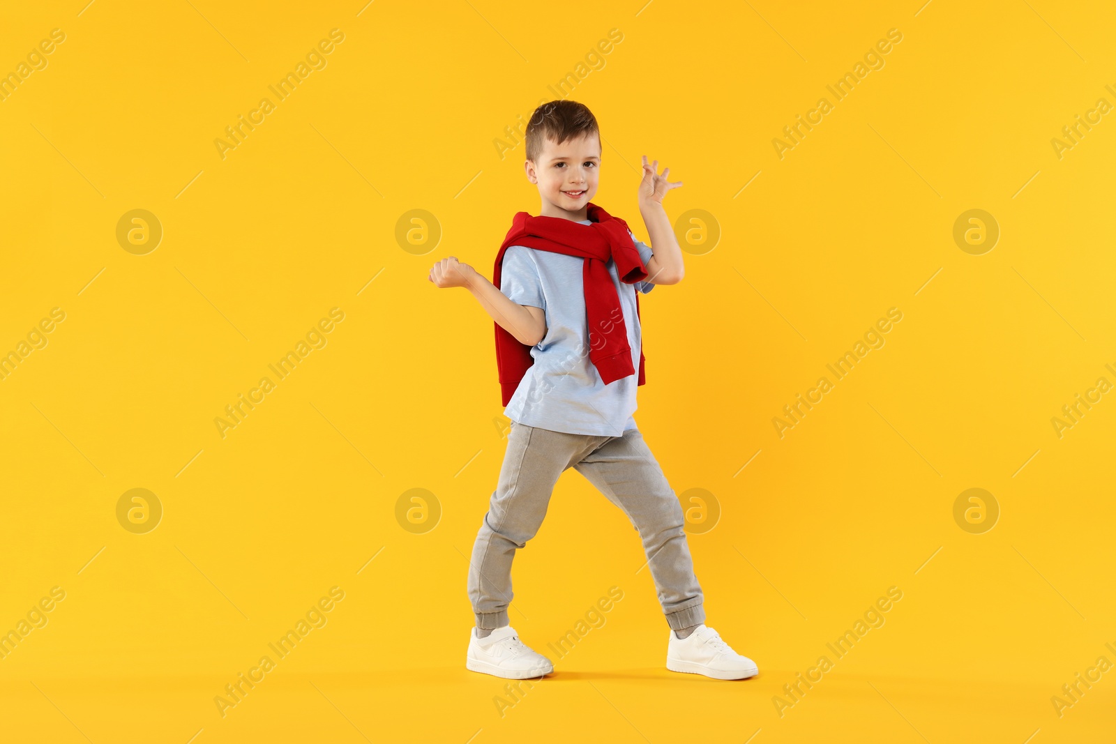 Happy little boy dancing on orange background Photo of Happy little boy dancing on orange background