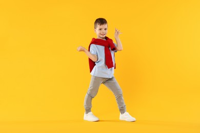 Photo of Happy little boy dancing on orange background