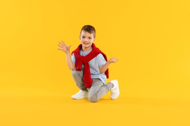 Photo of Happy little boy dancing on orange background