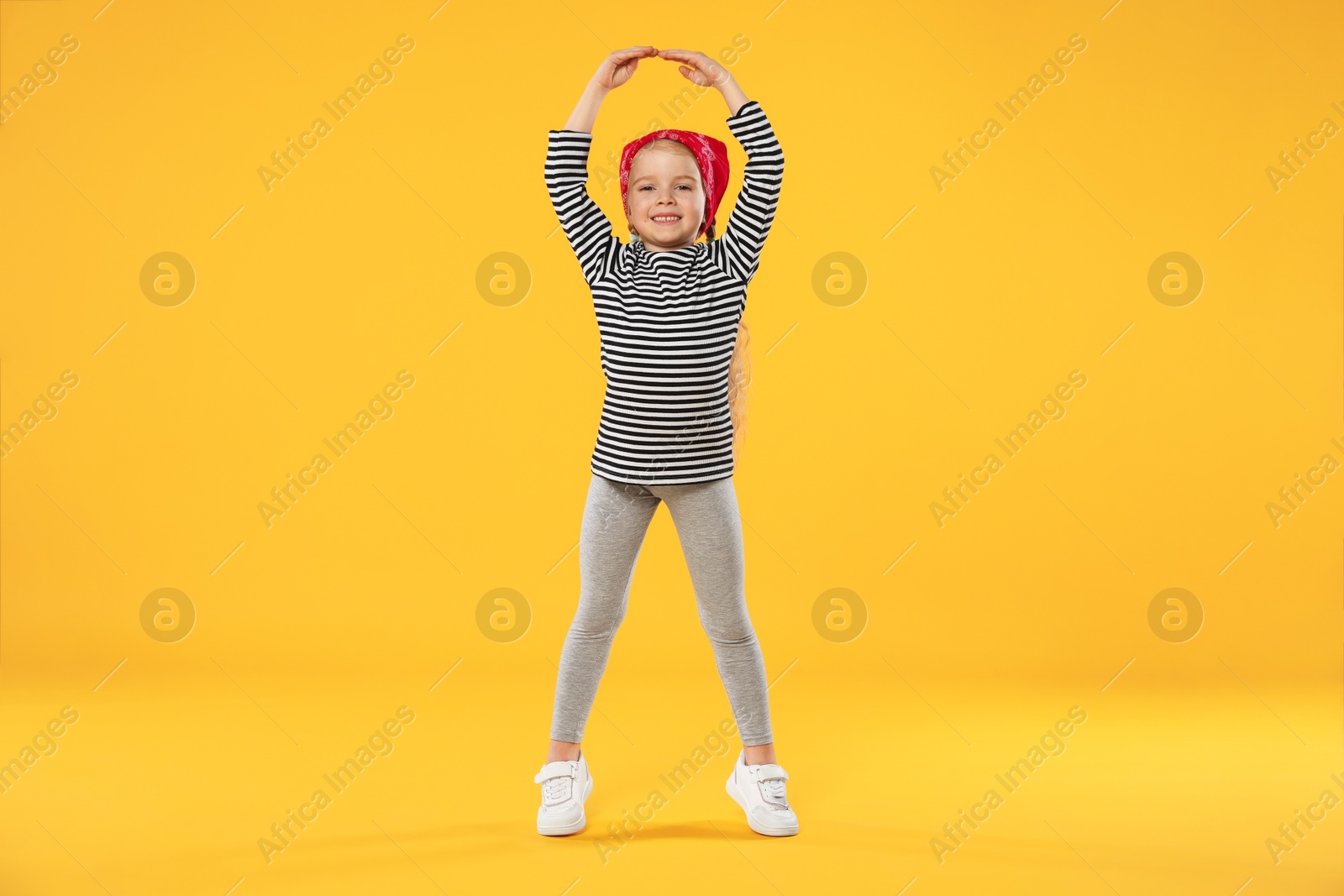 Cute little girl dancing on orange background Photo of Cute little girl dancing on orange background