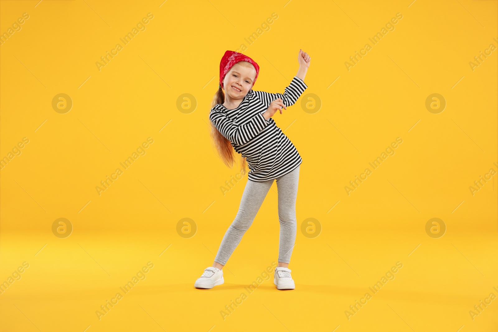 Cute little girl dancing on orange background Photo of Cute little girl dancing on orange background