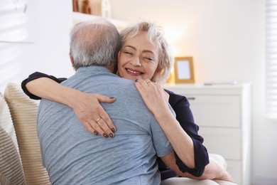 Photo of Lovely senior couple hugging on sofa at home