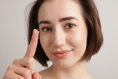 Photo of Woman with contact lens on light background, closeup