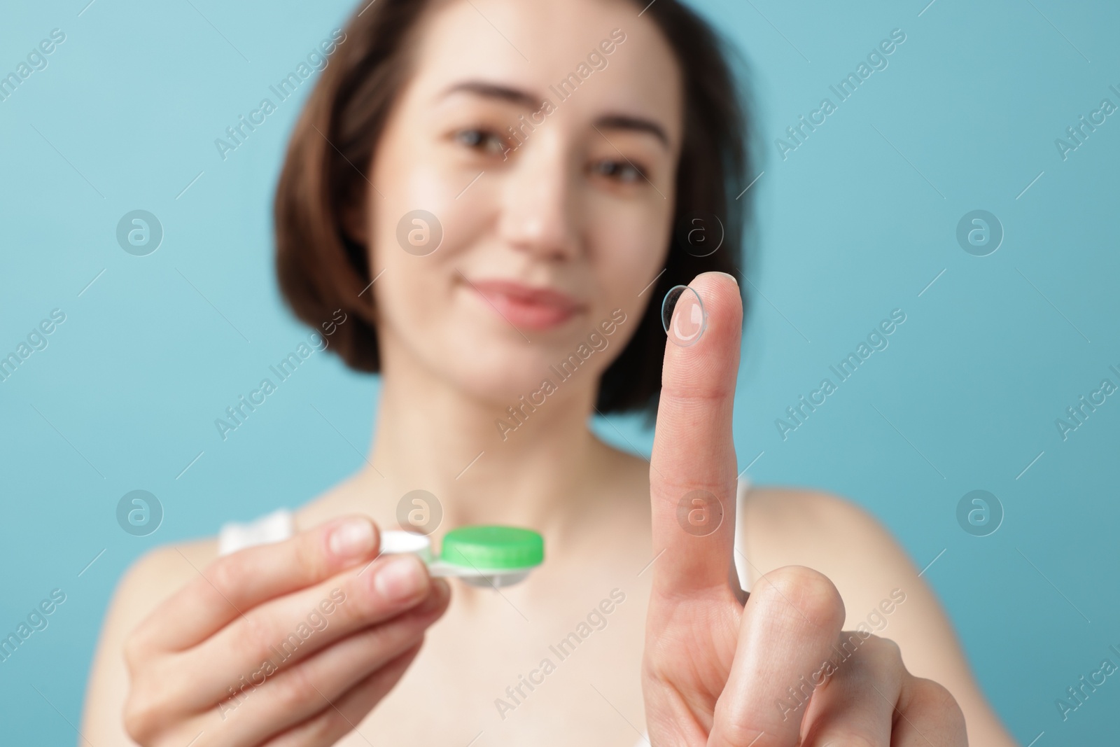 Woman with contact lens and case on light blue background, selective focus Photo of Woman with contact lens and case on light blue background, selective focus
