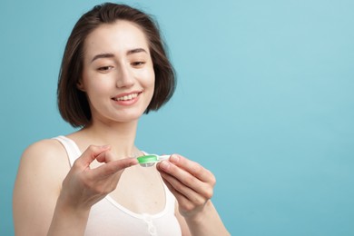 Photo of Woman with contact lens and case on light blue background. Space for text