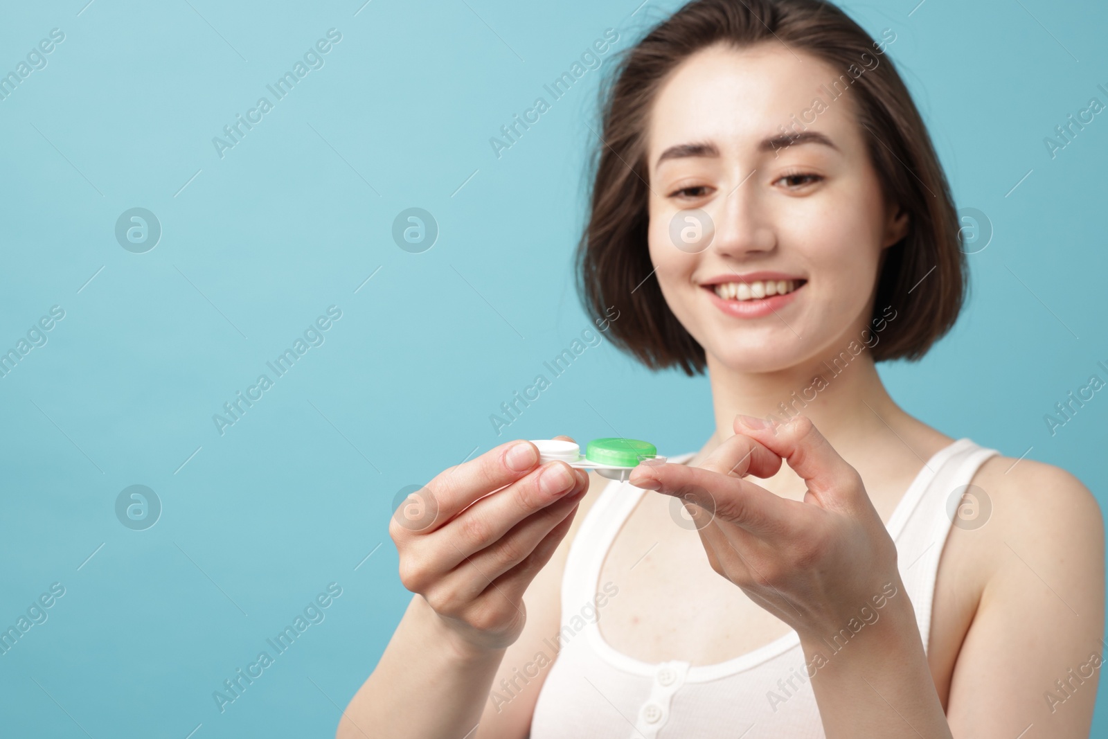 Woman with contact lens and case on light blue background. Space for text Photo of Woman with contact lens and case on light blue background. Space for text