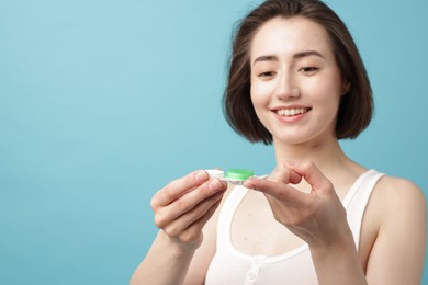 Photo of Woman with contact lens and case on light blue background. Space for text
