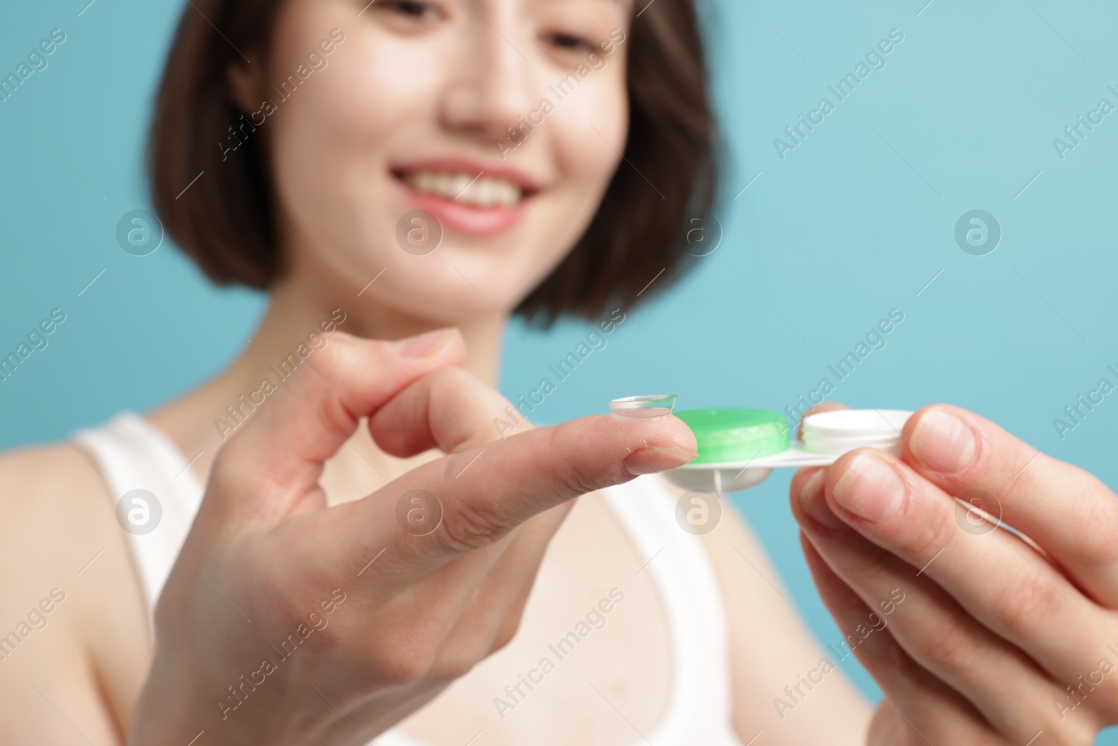 Woman with contact lens and case on light blue background, selective focus Photo of Woman with contact lens and case on light blue background, selective focus