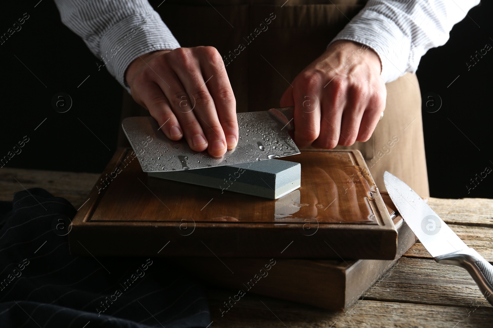 Man sharpening knife with sharpener on wooden table, closeup Photo of Man sharpening knife with sharpener on wooden table, closeup