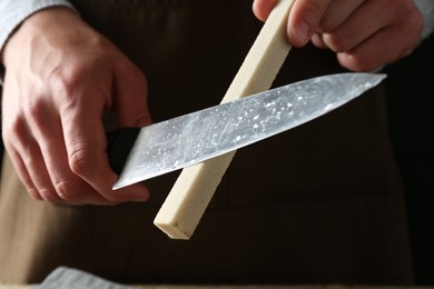 Photo of Man sharpening knife with sharpener, closeup view