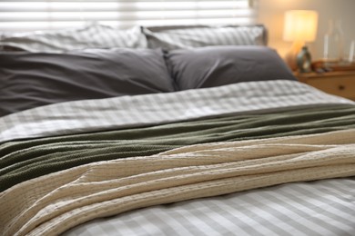 Photo of Comfortable bed with soft linens and blankets in room, closeup. Home textile