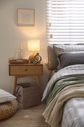 Photo of Comfortable bed with soft linens, blankets and bedside table in room. Home textile