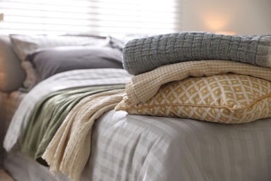 Photo of Comfortable bed with soft linens and blankets in room, closeup. Home textile