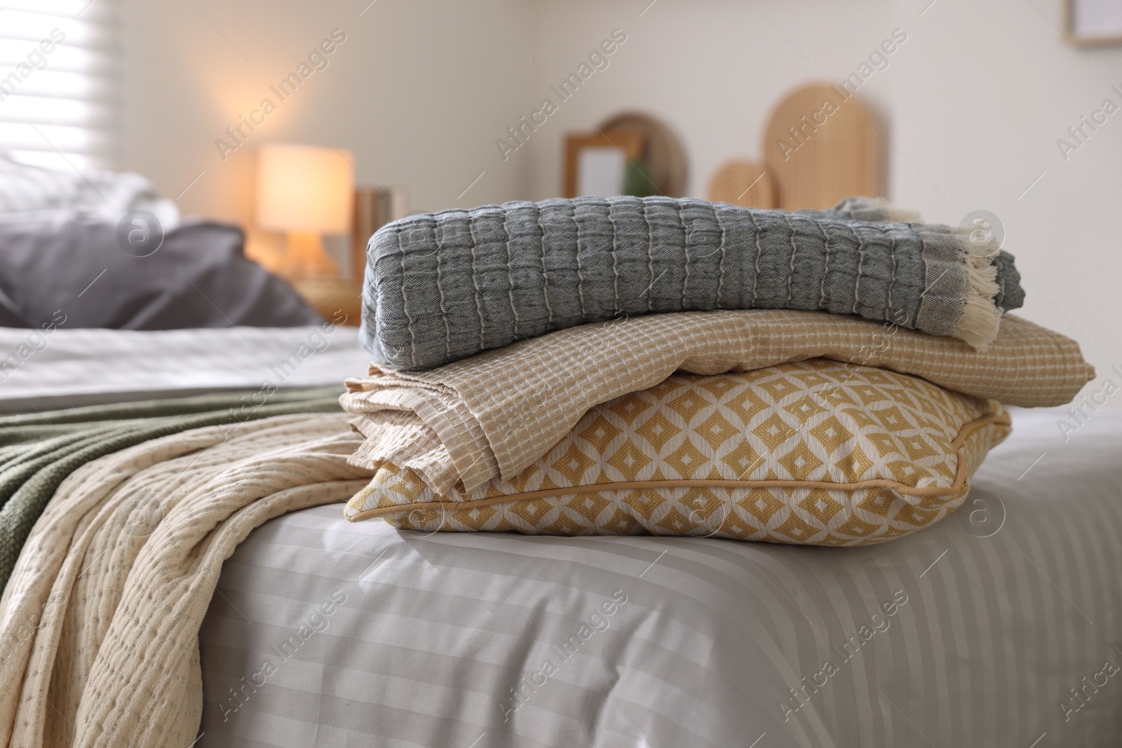 Comfortable bed with soft linens and blankets in room, closeup. Home textile Photo of Comfortable bed with soft linens and blankets in room, closeup. Home textile