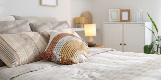 Photo of Comfortable bed with soft linens in room, closeup. Home textile