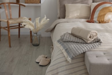 Photo of Comfortable bed with soft linens, slippers and decor in room. Home textile