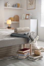 Photo of Comfortable bed with soft linens, blankets and books in room. Home textile
