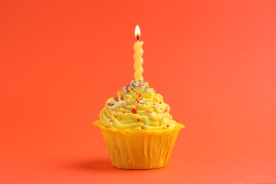 Photo of Burning candle in cupcake on orange background
