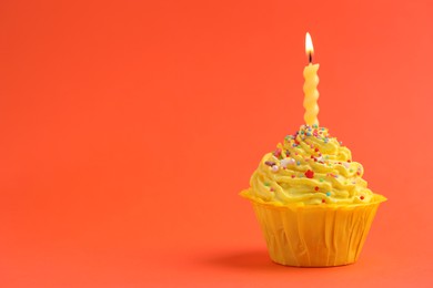 Photo of Burning candle in cupcake on orange background, space for text
