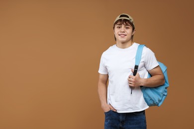 Photo of Teenage boy with backpack on brown background. Space for text