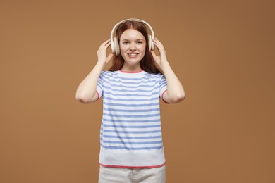 Photo of Teenage girl listening to music on brown background
