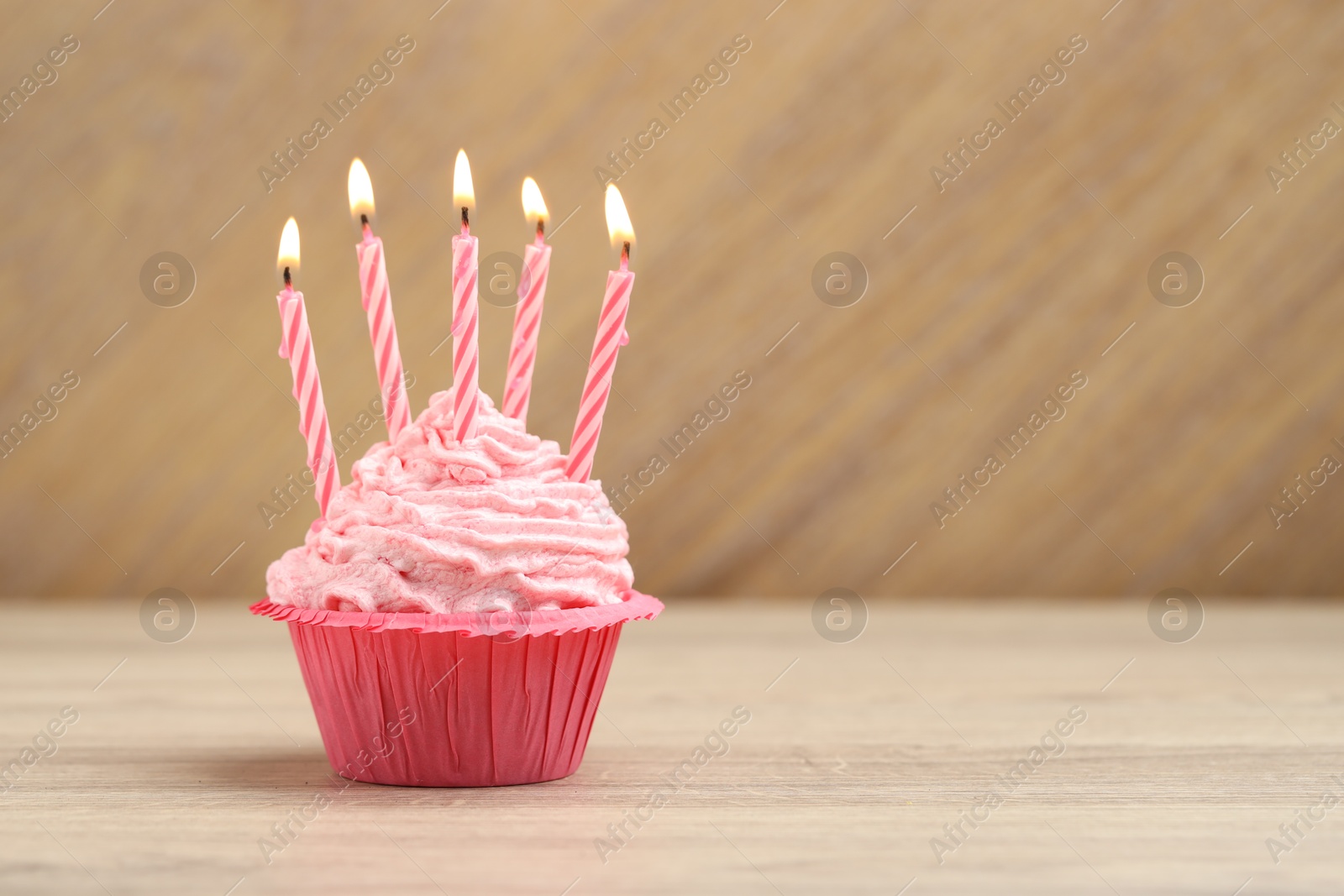 Burning candles in cupcake on wooden table, space for text Photo of Burning candles in cupcake on wooden table, space for text