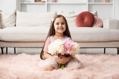 Photo of Cute little girl with bouquet of beautiful peonies on floor at home