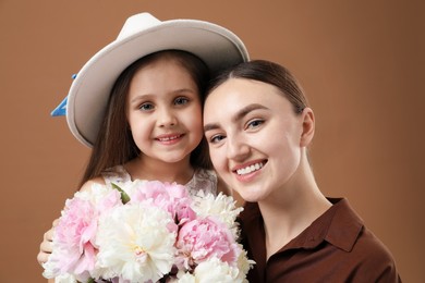 Photo of Mother and her daughter with bouquet of beautiful peonies on brown background
