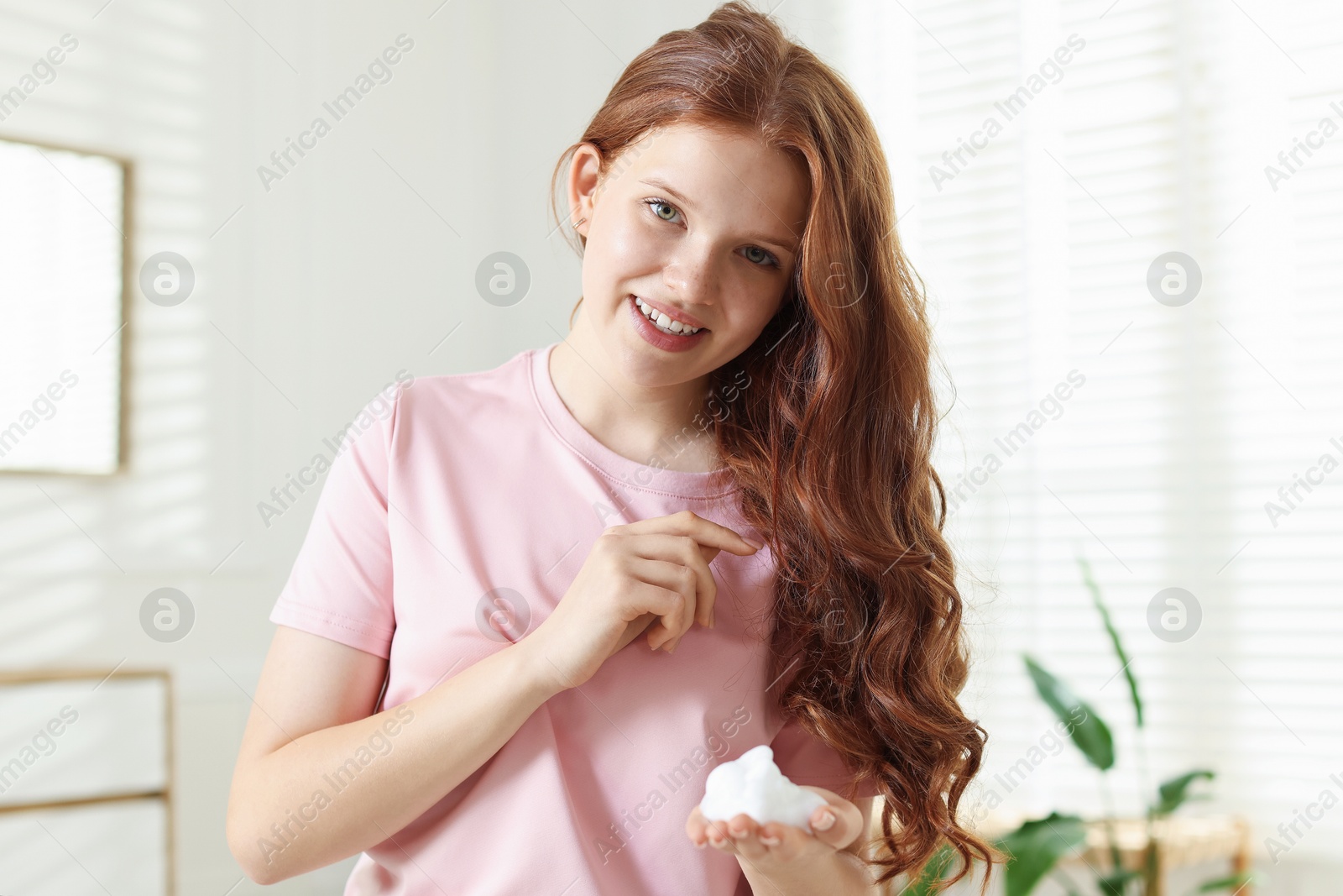 Smiling teenage girl with hair mousse at home Photo of Smiling teenage girl with hair mousse at home