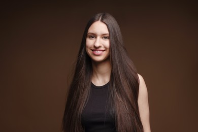 Photo of Portrait of smiling teenage girl with healthy long hair on brown background