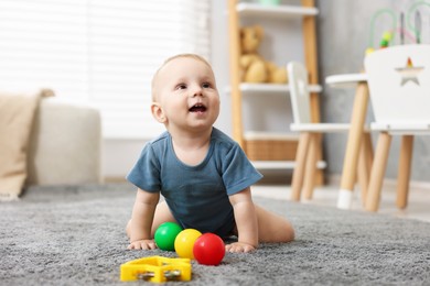 Photo of Cute little baby playing with toys in room