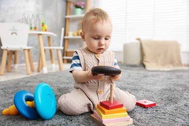 Photo of Cute little baby playing with toys in room