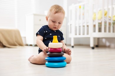 Photo of Cute little baby playing with toy pyramid in room, space for text
