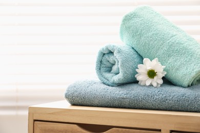 Photo of Soft towels and chrysanthemum flower on wooden cabinet indoors, space for text