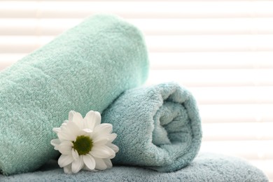 Photo of Soft towels and chrysanthemum flower indoors, closeup. Space for text