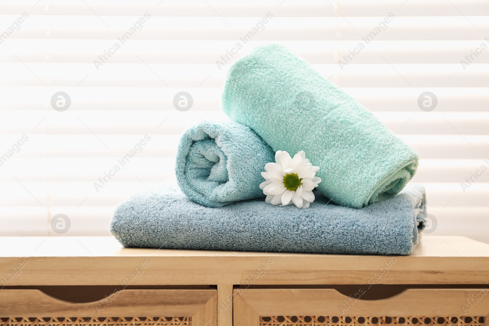 Soft towels and chrysanthemum flower on wooden cabinet indoors Photo of Soft towels and chrysanthemum flower on wooden cabinet indoors