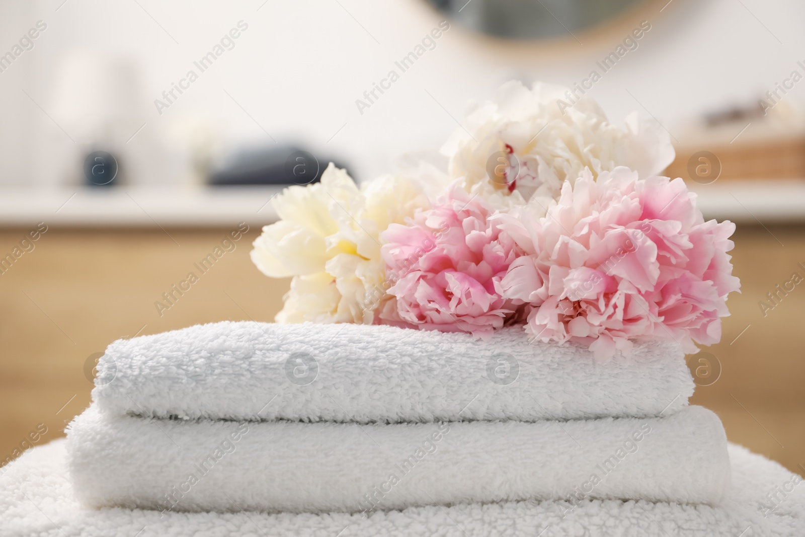 Stack of soft towels and peony flowers indoors, closeup Photo of Stack of soft towels and peony flowers indoors, closeup