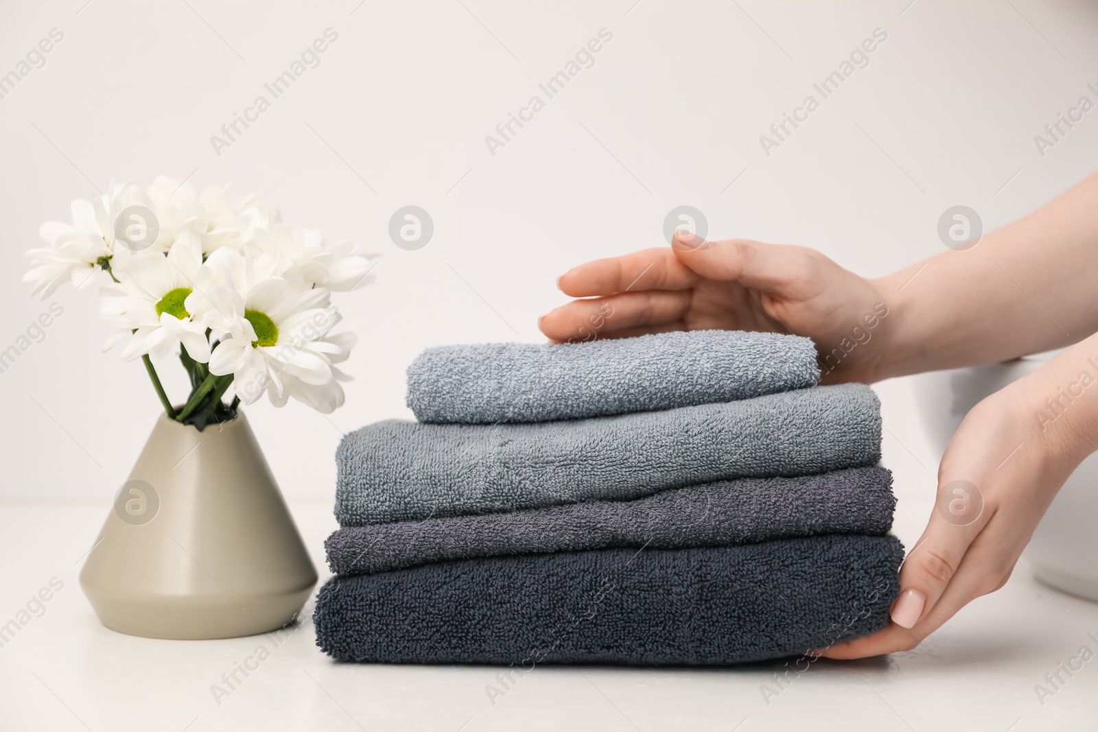 Woman with soft towels at white table indoors, closeup Photo of Woman with soft towels at white table indoors, closeup