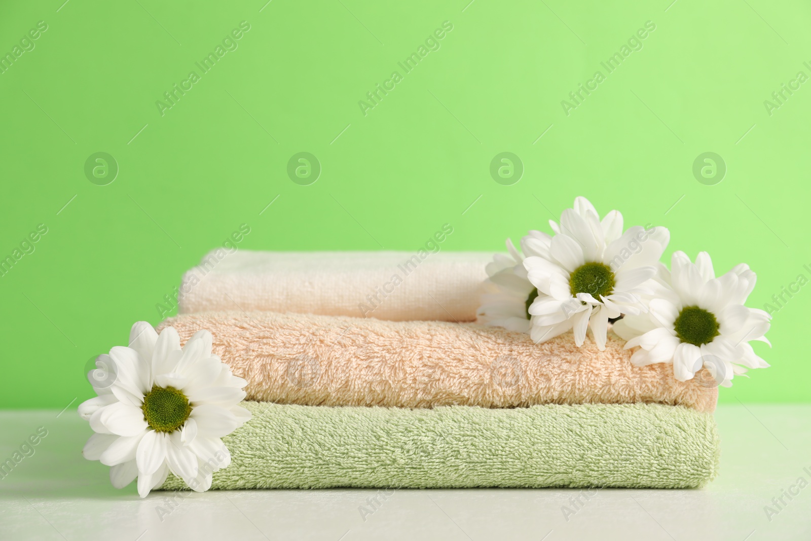 Soft towels and chrysanthemum flowers on green background, closeup Photo of Soft towels and chrysanthemum flowers on green background, closeup