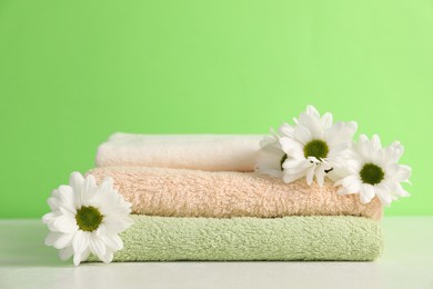 Photo of Soft towels and chrysanthemum flowers on green background, closeup