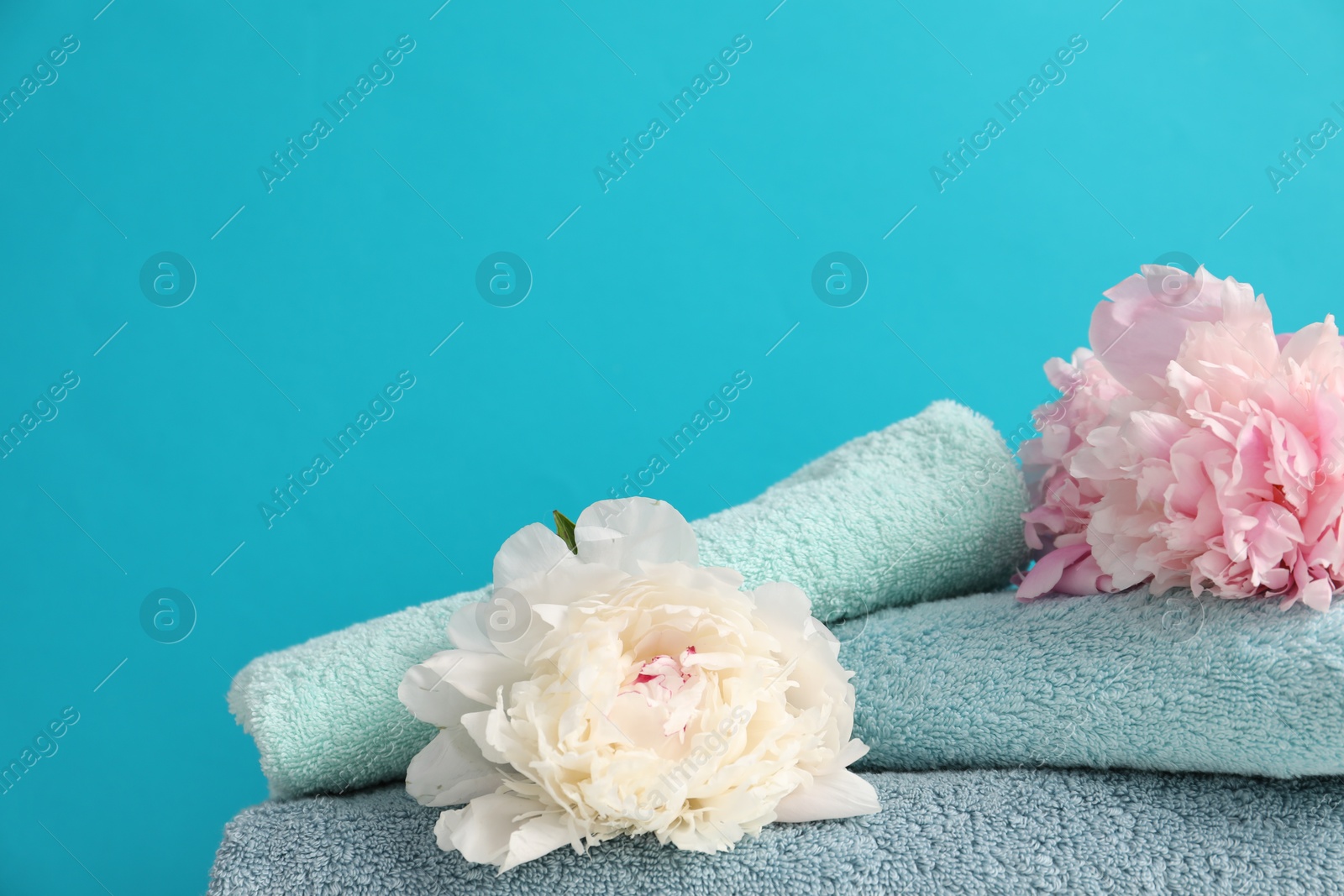 Soft towels and peony flowers on light blue background, closeup Photo of Soft towels and peony flowers on light blue background, closeup