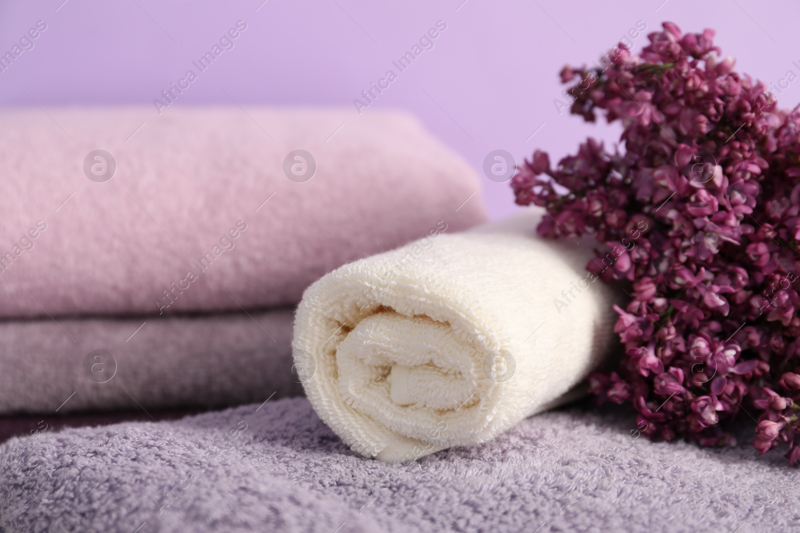 Soft towels and lilac flowers on violet background, closeup Photo of Soft towels and lilac flowers on violet background, closeup